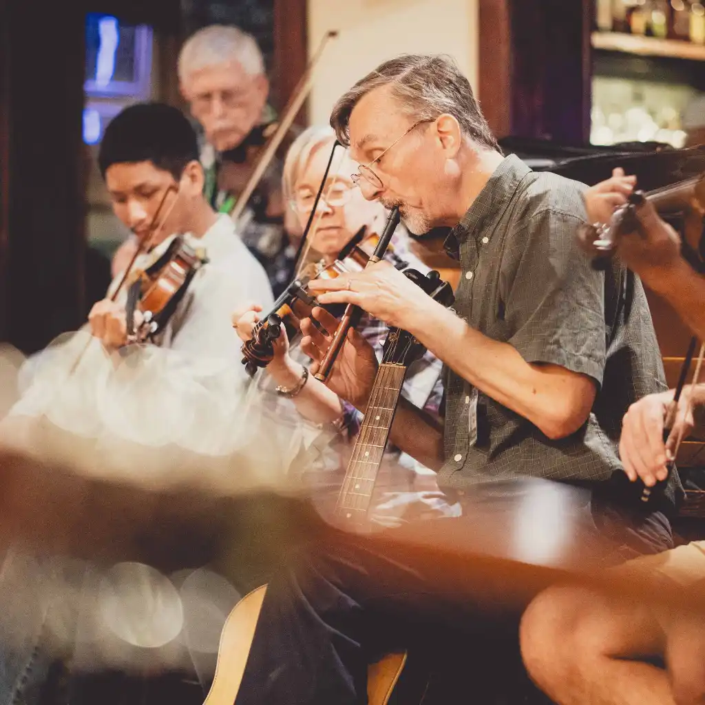 Man playing a pennywhistle in a traditional Irish music session